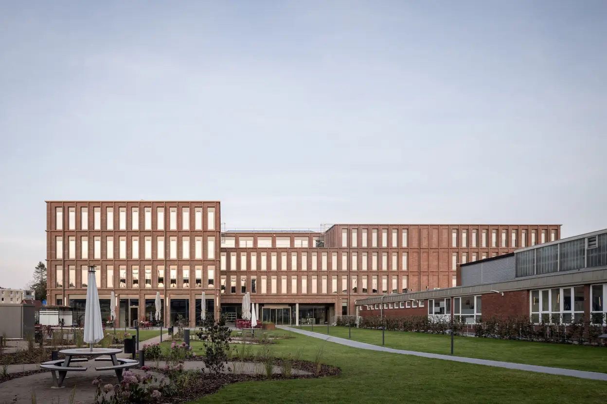 Rückansicht der modernen Firmenzentrale von Queisser Pharma mit begrüntem Innenhof im Vordergrund.