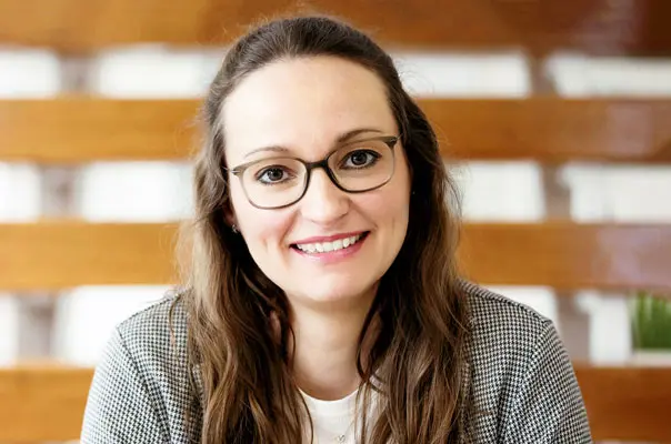 Lächelnde Mitarbeiterin mit Brille im modernen Innenraum