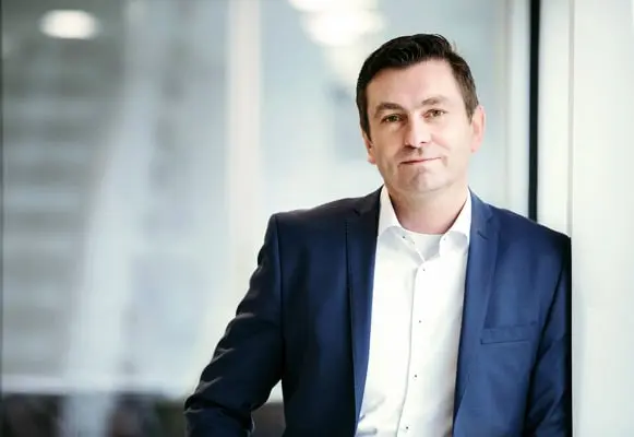 Mann im blauen Anzug vor einer Glaswand