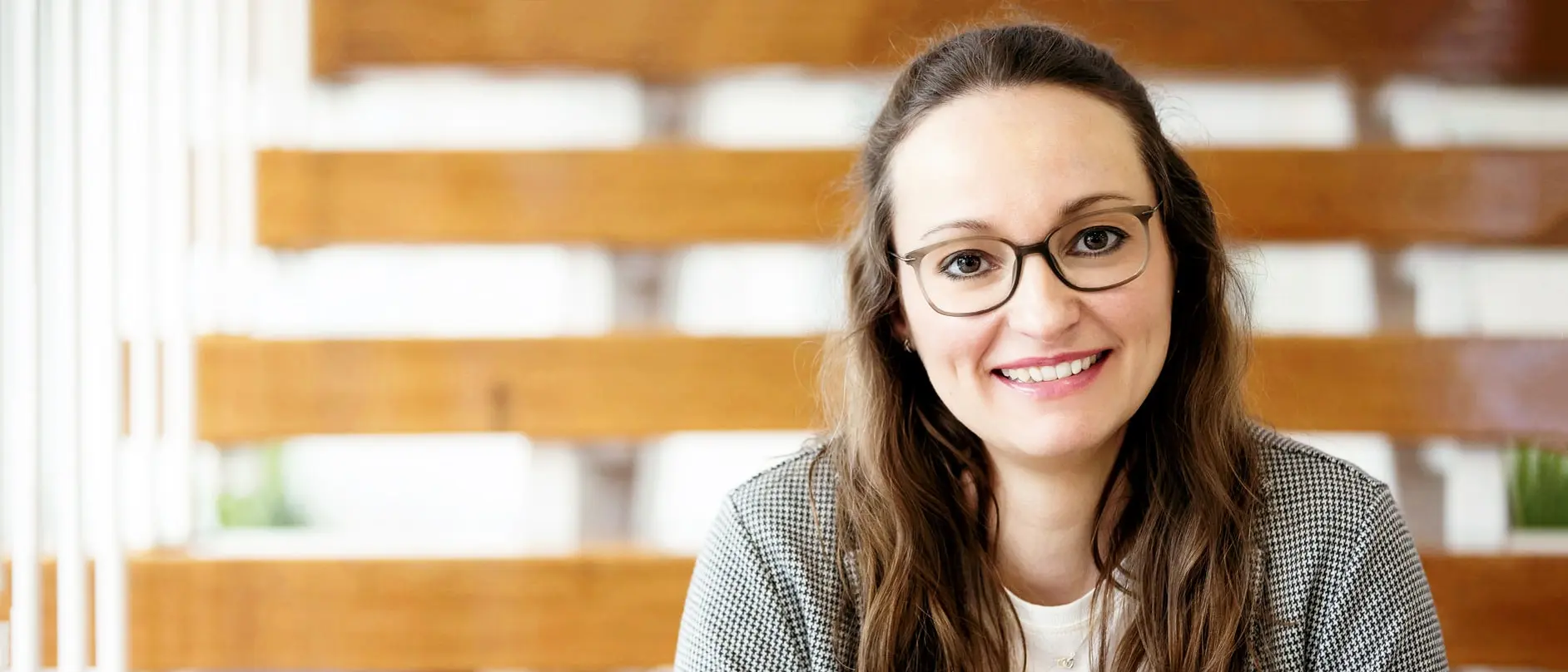 Lächelnde Mitarbeiterin mit Brille im modernen Innenraum