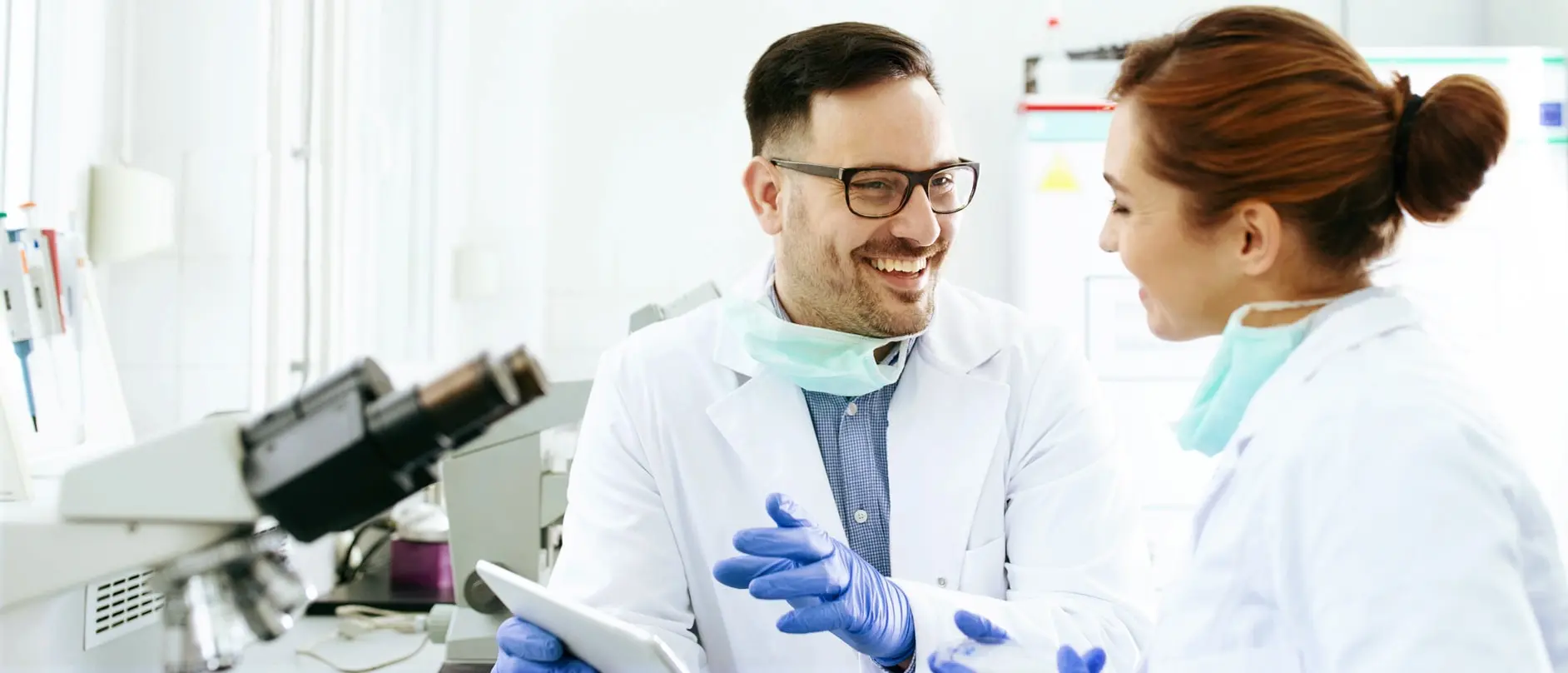 Gespräch zwischen zwei Mitarbeitern im Labor vor einem Mikroskop