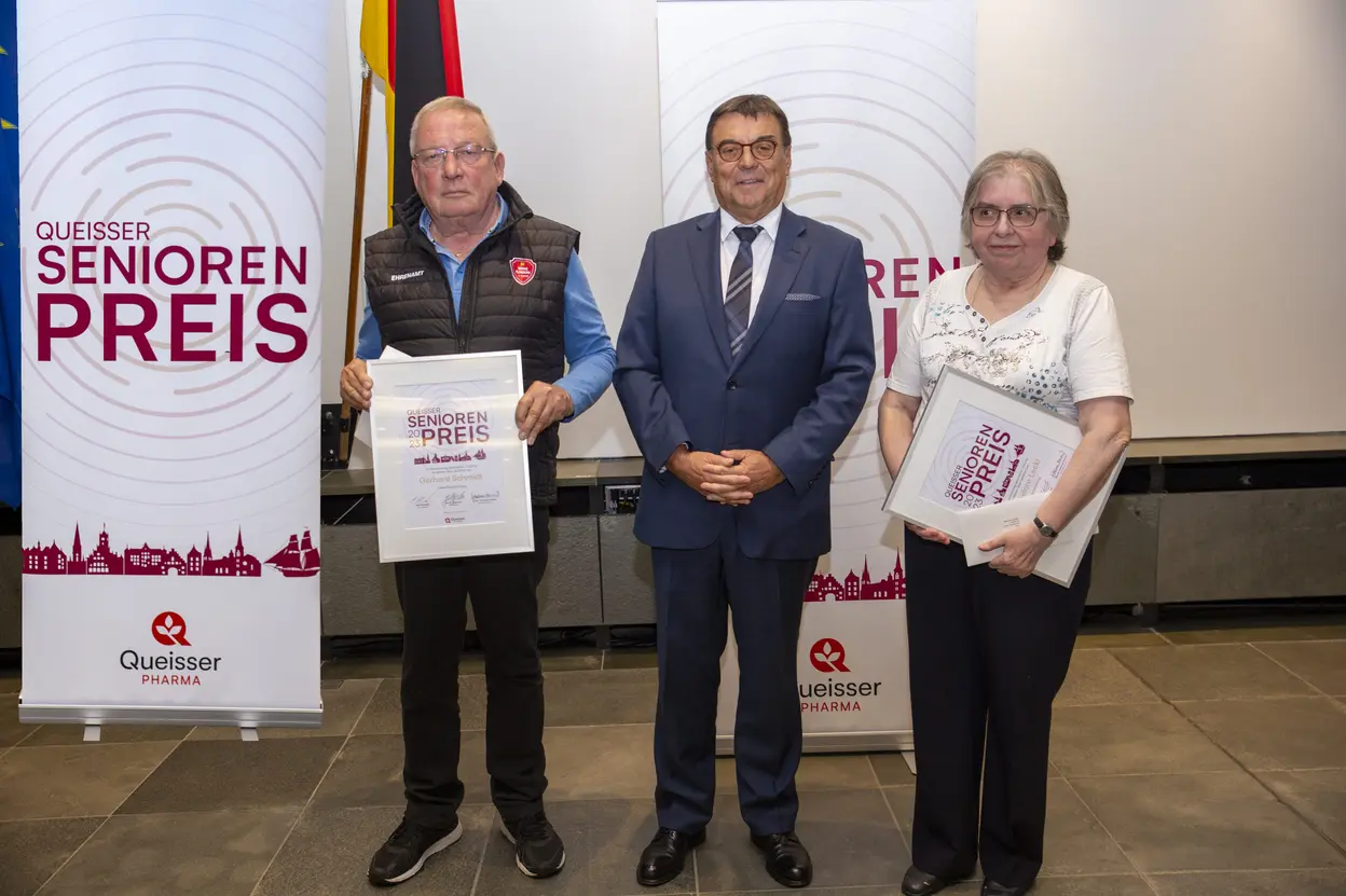 Geschäftsführer Jan Kuskowski und zwei Preisträger stehen vor Roll-ups mit der Aufschrift ‚Queisser Senioren Preis‘; die Preisträger halten Urkunden in den Händen.