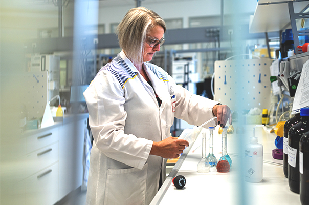 Frau im weißen Laborkittel bei der Analyse von Proben im Labor.